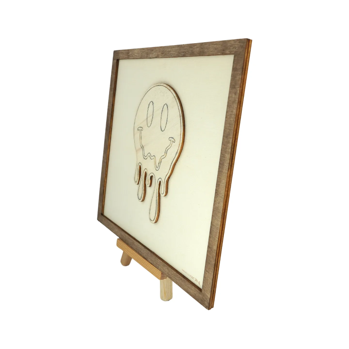 Customizable wall art frame of a melting smiley in cut and engraved wood side view with easel Woodillusion