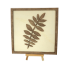 Customizable wall art frame of a leaf in cut and engraved wood front view with easel Woodillusion